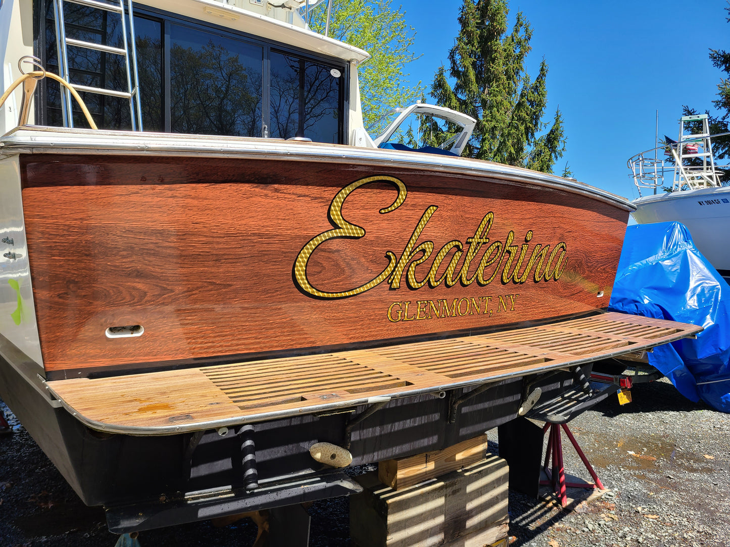 Teak wood boat wrap installed on transom. Gold leaf vinyl lettering installed over vinyl wrap for boat name and port of call. Boat signs.